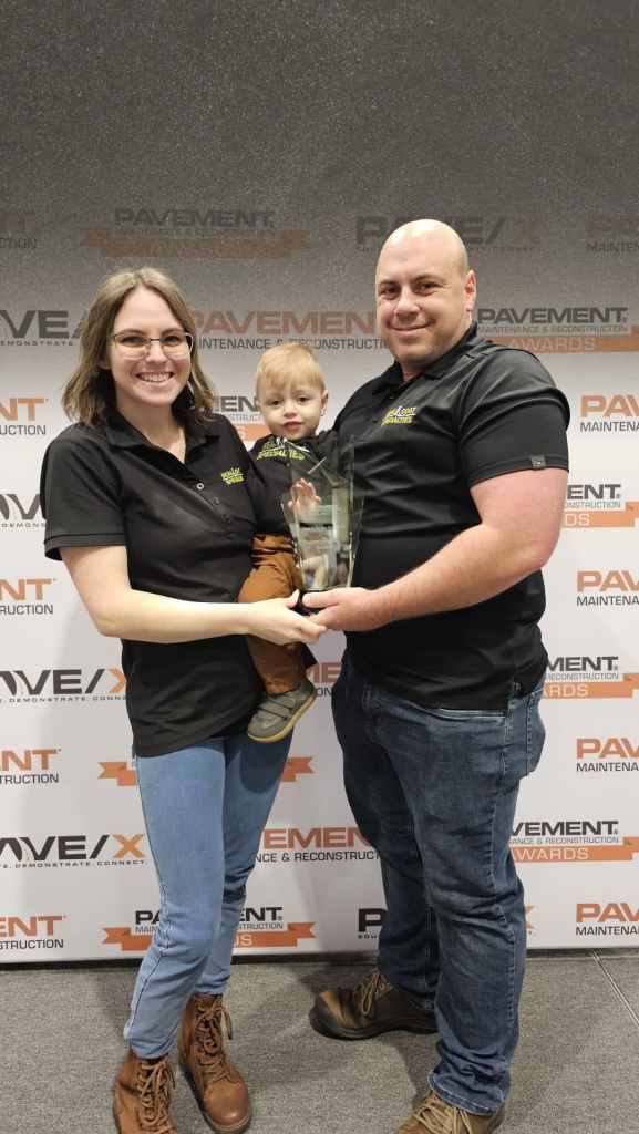 Cody Helstern and family of Sealcoat Specialties accepting back-to-back national Seal & Stripe Award at PAVE/X in New Orleans