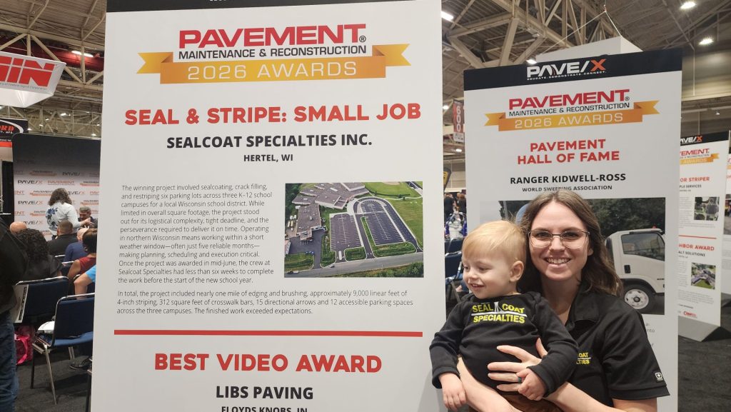 Sealcoat Specialties family at the PAVE/X event next to the featured article about their national Seal & Stripe Award-winning project.